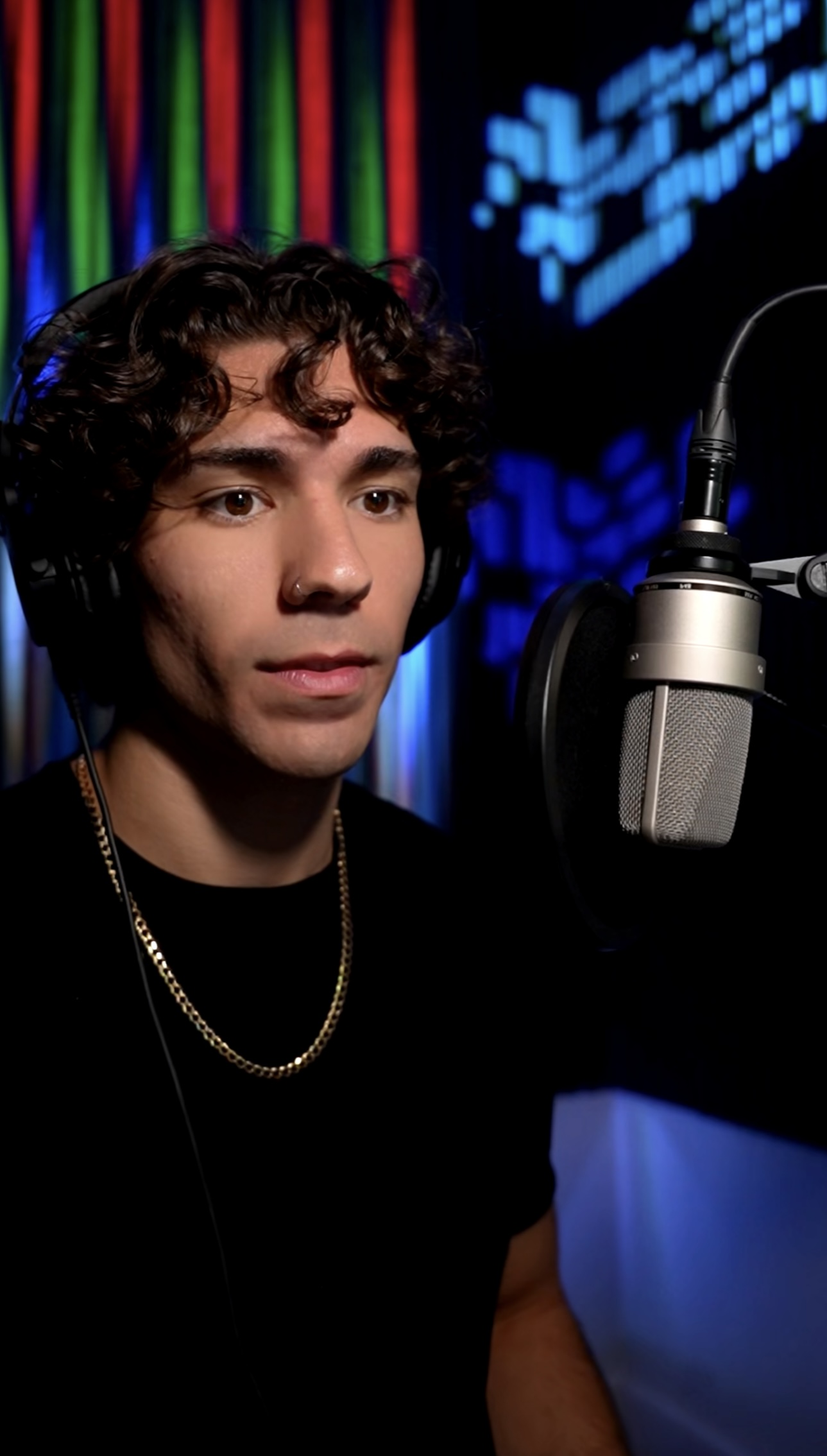 Cam wearing headphones beside his studio microphone